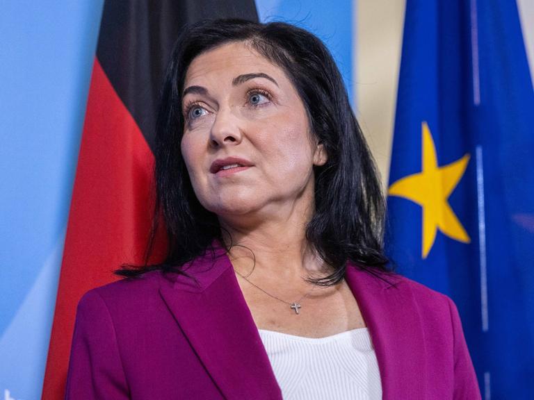 Wirtschafts- und Energieministerin Katherina Reiche trägt ein pinkes Jackett, im Hintergrund sind eine blaue Wand sowie die Deutschland- und die EU-Flagge zu sehen.