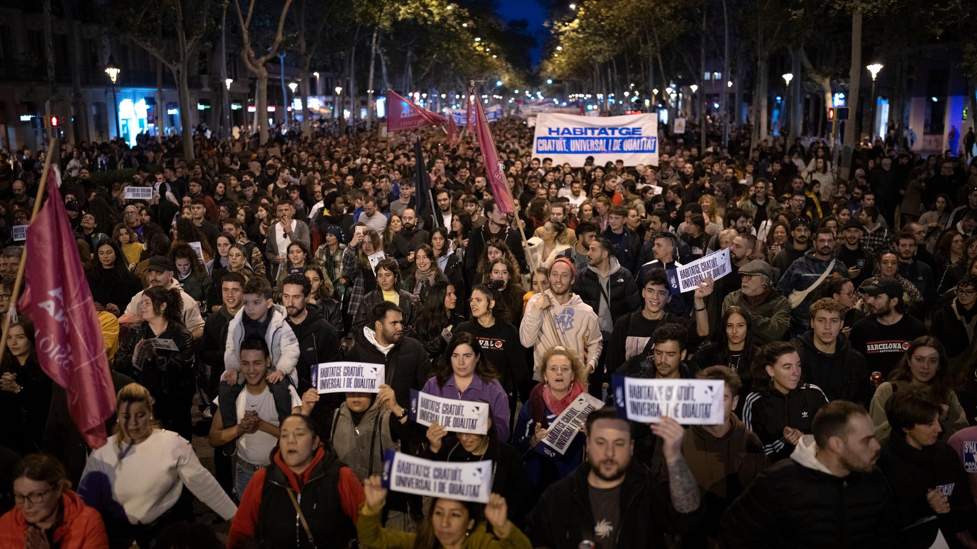 An den Demonstrationen in Barcelona für bezahlbaren Wohnraum beteiligten sich viele Menschen. Sie halten Transparente hoch und gehen durch eine Straße.