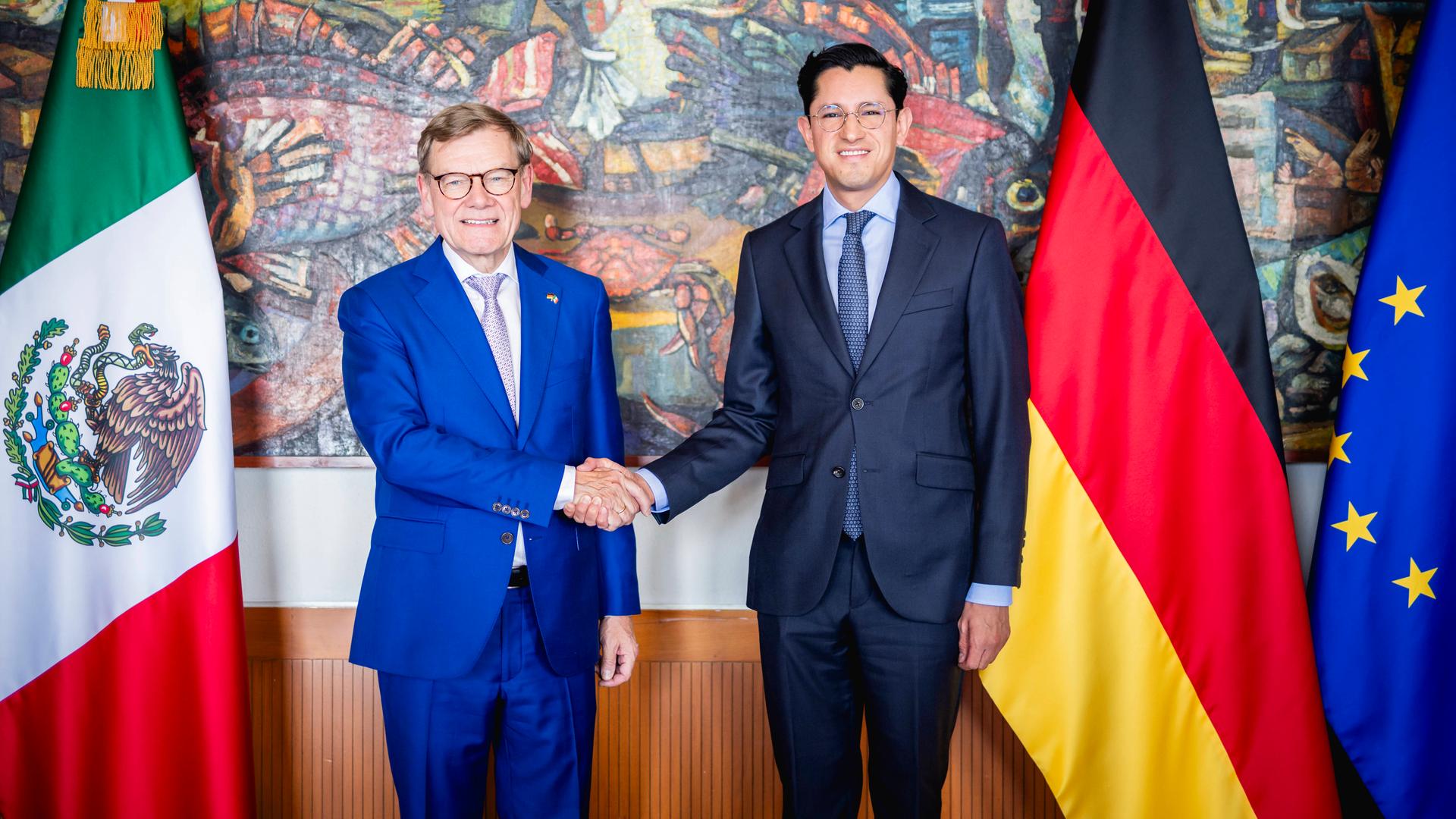 Wadephul und Velasco stehen nebeneinander und schütteln sich die Hand. Sie schauen lächelnd in Richtung der Kamera. Neben ihnen sind die Flaggen Deutschlands und Mexikos sowie die Europa-Flagge zu sehen.