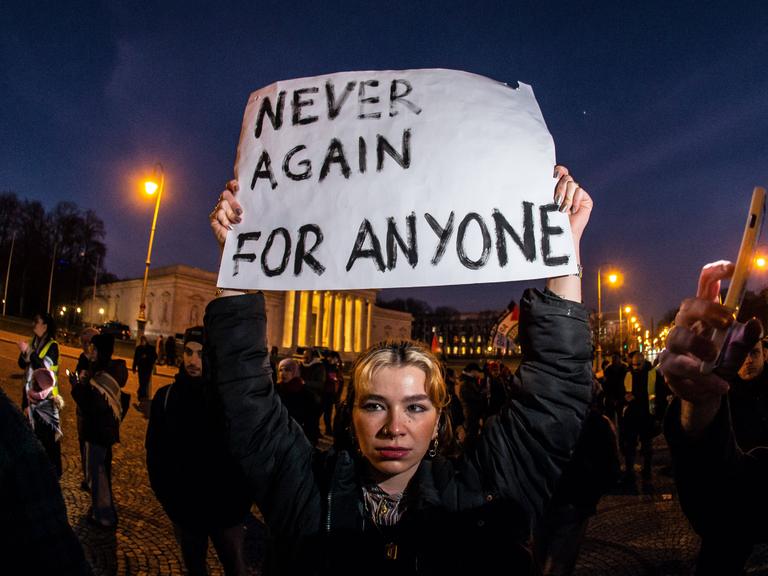 Pro-Palästina Demo: Eine Frau hält ein Schild mit der Aufschrift "Never again for anyone" in die Höhe.