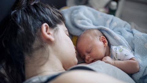 Nahaufnahme eines neugeborenen Babys, das mit geschlossenen Augen auf der Brust der Mutter liegt. Nahaufnahme eines neugeborenen Babys, das mit geschlossenen Augen auf der Brust der Mutter liegt.