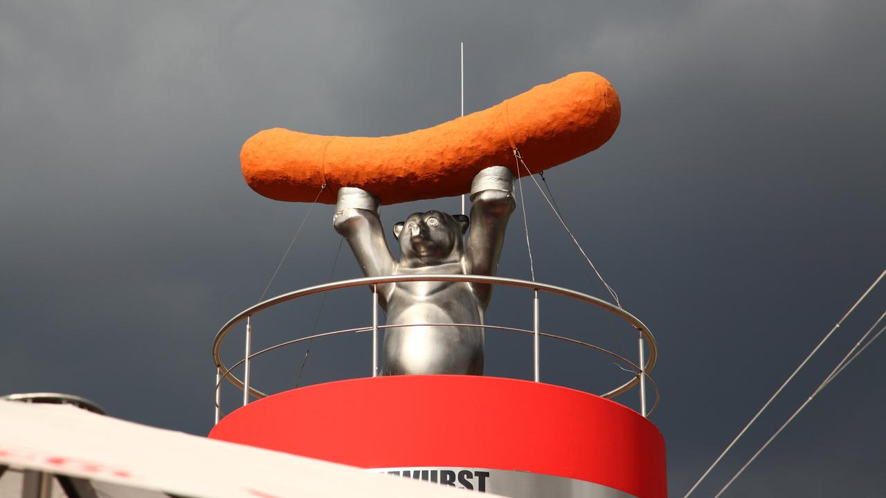 Skulptur eines Bären mit Wurst auf einem Imbiss in Berlin, vor wolkenverhangenem Himmel