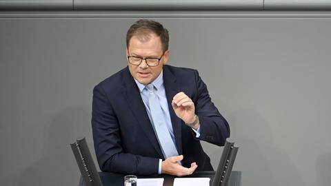 Umweltminister Carsten Schneider spricht im Plenarsaal im Bundestag zu den Abgeordneten. Er hebt beim Reden die linke Hand.