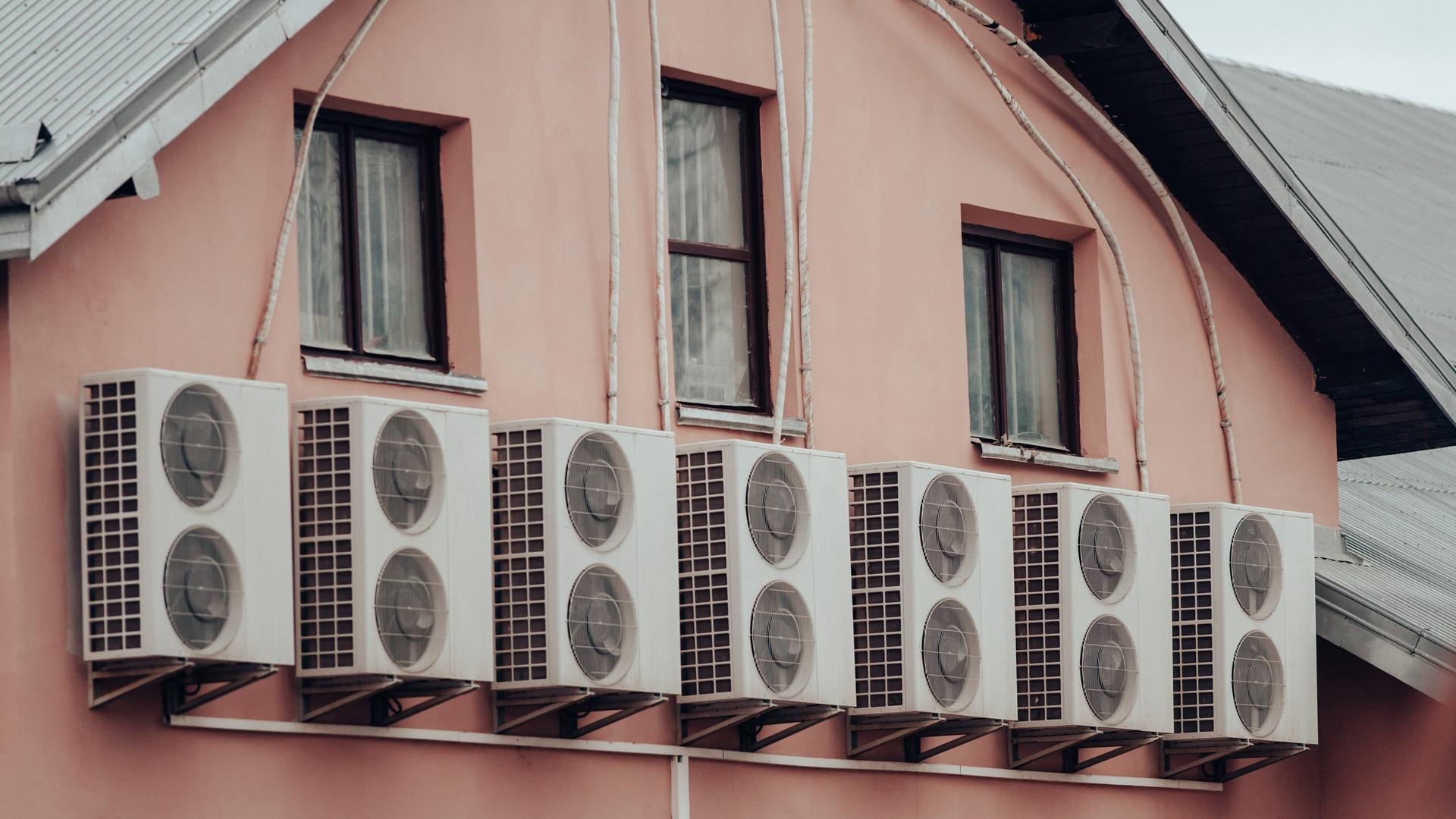 Mehrere Klimaanlagen, die außen an der Fassade eines Wohnhauses befestigt wurden.
