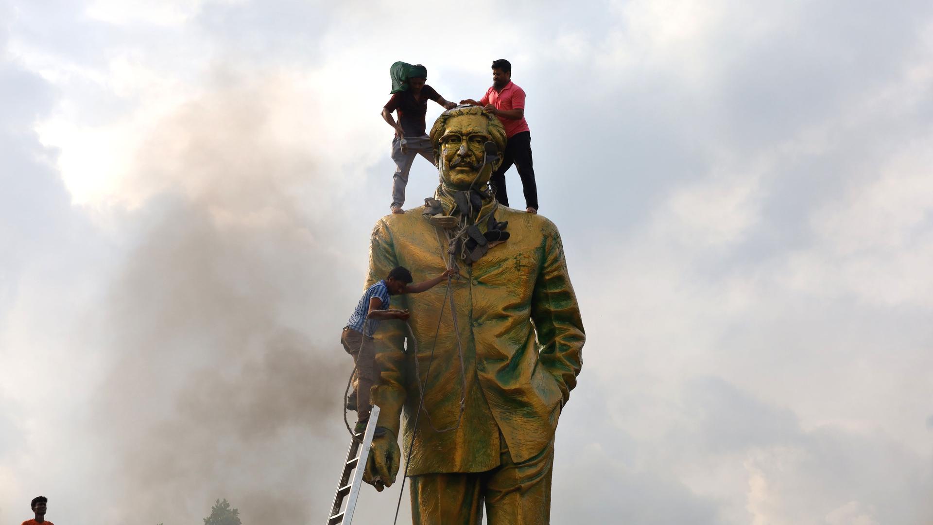 Protestierende in Dhaka, Bangladesh, besteigen die Statue des Volkshelden Sheikh Mujiban Rahman, Vater der aus dem Amt gejagten Regierungschefin Sheikh Hasina