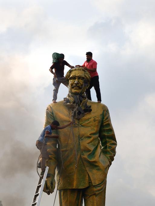 Protestierende in Dhaka, Bangladesh, besteigen die Statue des Volkshelden Sheikh Mujiban Rahman, Vater der aus dem Amt gejagten Regierungschefin Sheikh Hasina