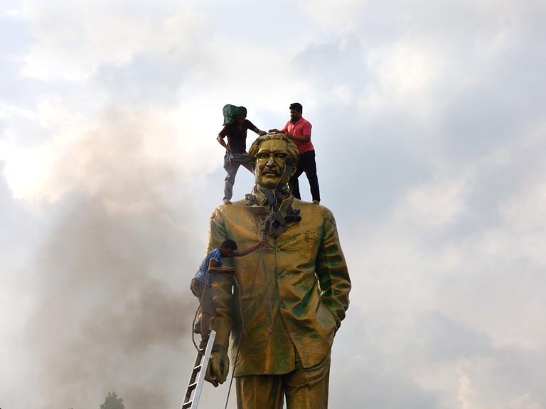 Protestierende in Dhaka, Bangladesh, besteigen die Statue des Volkshelden Sheikh Mujiban Rahman, Vater der aus dem Amt gejagten Regierungschefin Sheikh Hasina