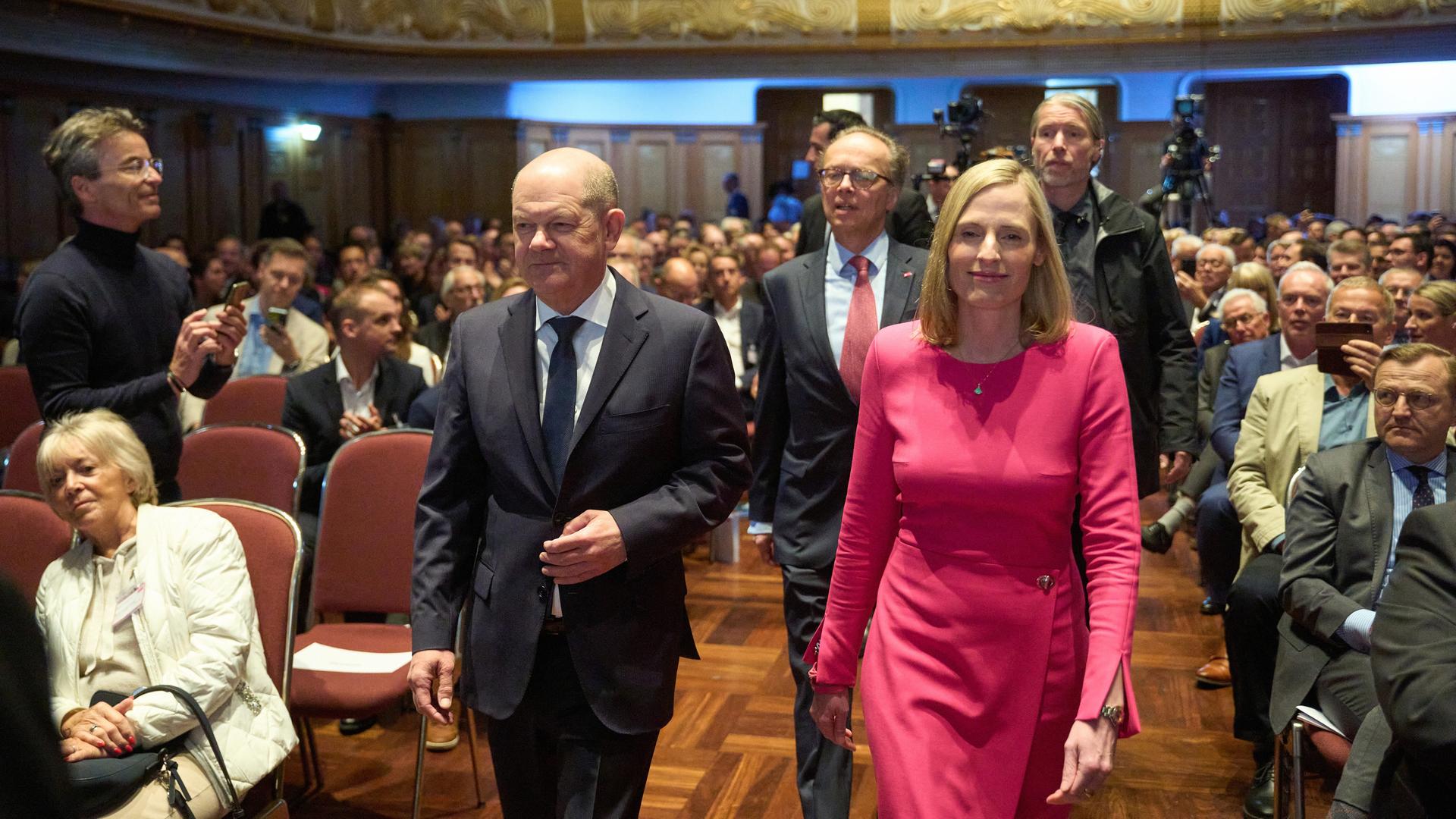 Bundeskanzler Olaf Scholz geht mit Hauptgeschäftsführer Albrecht von der Hagen und Präsidentin Marie Christine Ostermann vom Verband "Die Familienunternehmen" in einen Saal hinein.