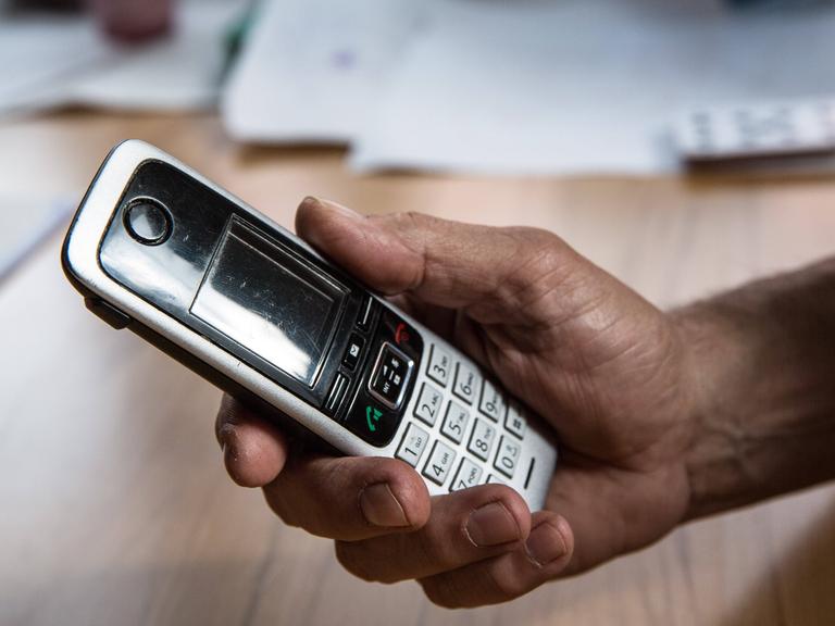 Die Hand eines älteren Menschen hält ein Telefon in der Hand. Vor allem Seniorinnen und Senioren werden Opfer von Telefonbetrug