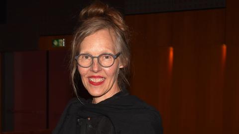 Porträt von Donata Wenders vor dunklem Hintergrund. Sie lacht in die Kamera.