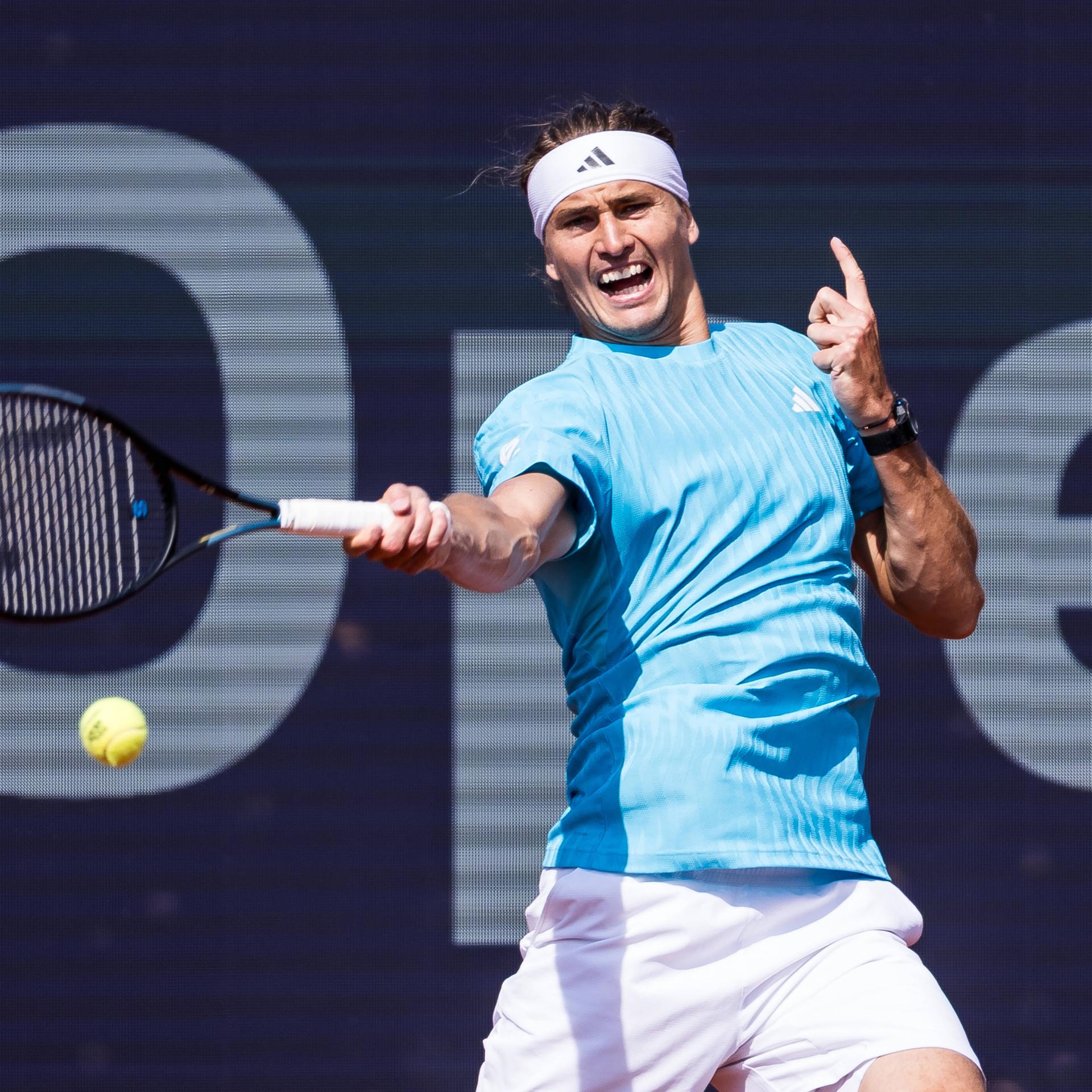 Alexander Zverev steht in München im Viertelfinale. Er schlägt mit der rechten Hand einen Ball und zeigt mit dem Zeigefinger der linken Hand nach oben.