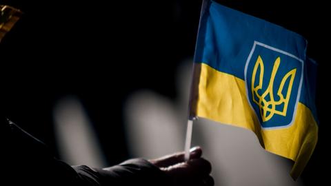 Eine Person hält eine ukrainische Flagge in der Hand während einer Demonstration in Rom gegen den russischen Krieg in der Ukraine.