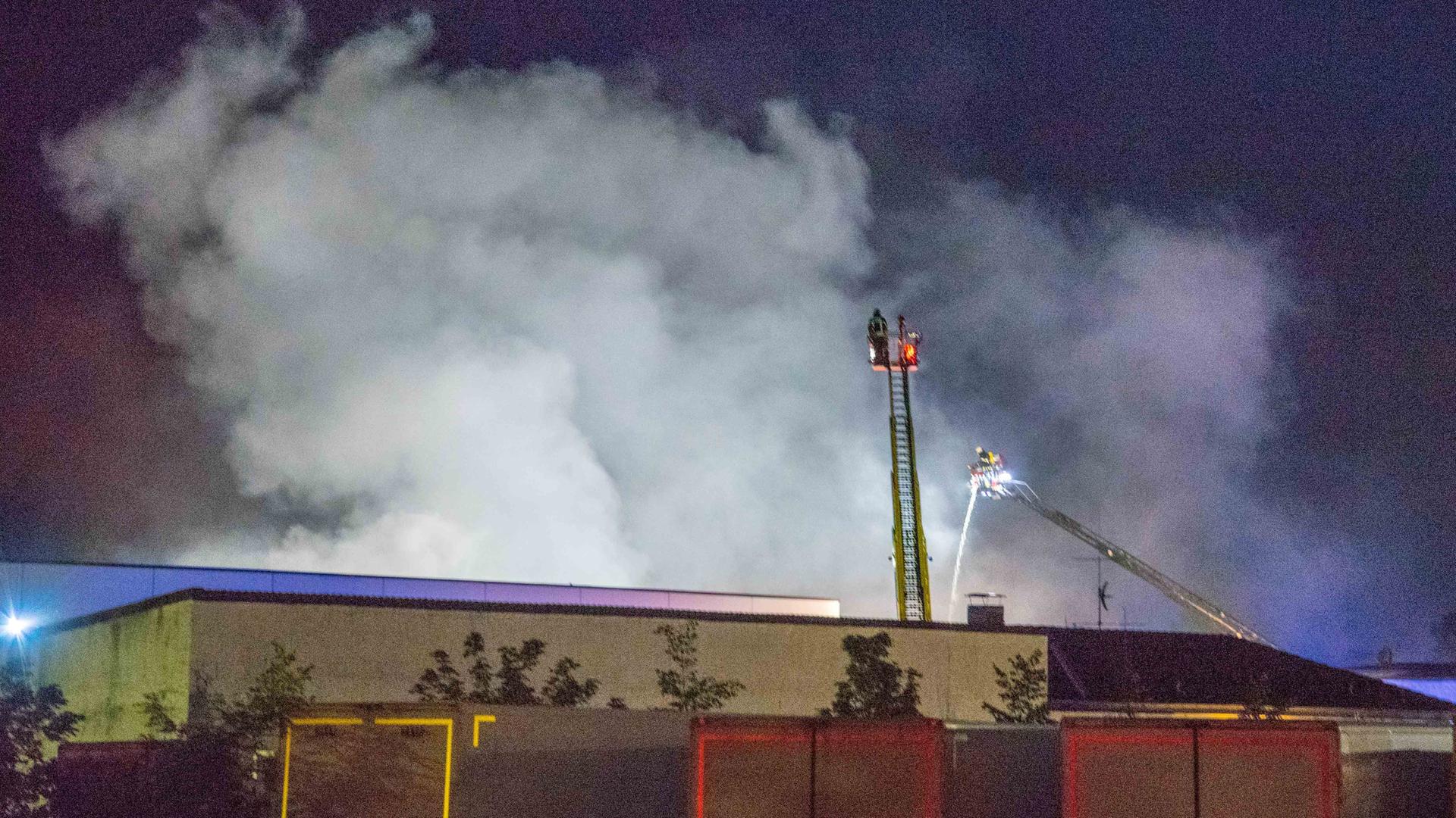 Eine große Rauchwolke. Feuerwehrleute auf zwei Leitern nähern sich ihr. Eine große Rauchwolke. Feuerwehrleute auf zwei Leitern nähern sich ihr.