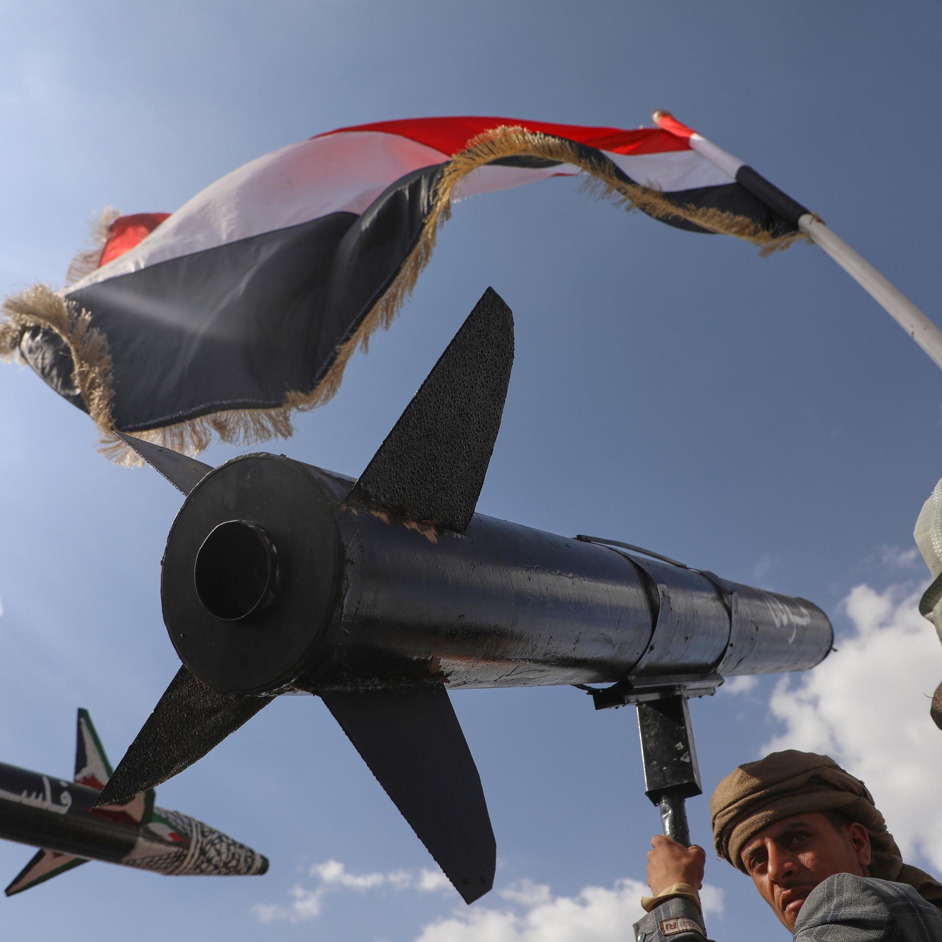 Jemen, Sanaa: Ein Huthi-Anhänger skandiert Slogans, während er eine Raketennachbildung trägt.