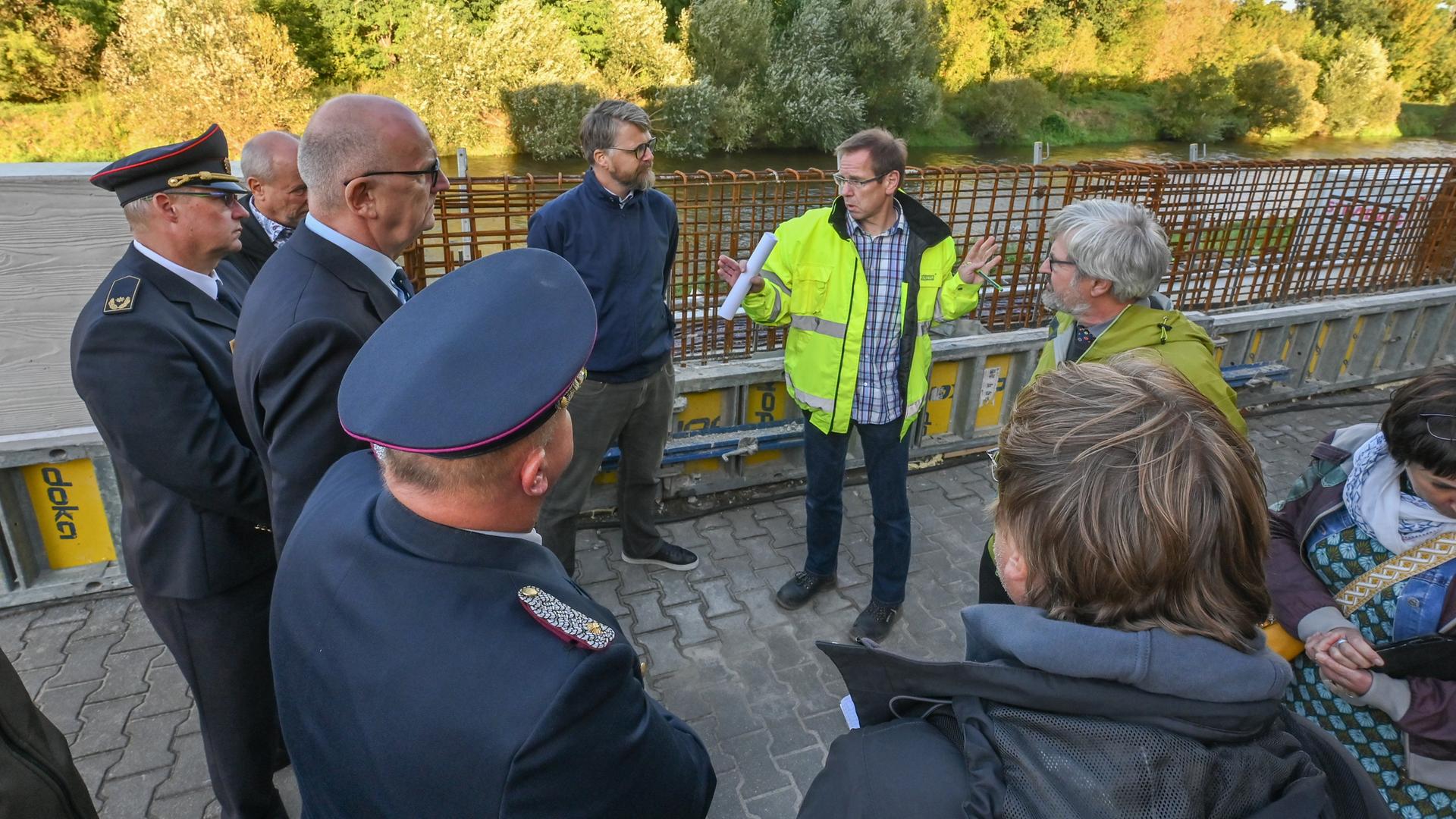 In Guben in Brandenburg stehen Ministerpräsident Dietmar Woidke (SPD, 3.v.l) und Umweltminister Axel Vogel (Bündnis 90/Die Grünen, hinten r) sowie Vertreter von Behörden an einer Baustelle für eine Hochwasserspundwand am Grenzfluss Neiße. In Guben in Brandenburg stehen Ministerpräsident Dietmar Woidke (SPD, 3.v.l) und Umweltminister Axel Vogel (Bündnis 90/Die Grünen, hinten r) sowie Vertreter von Behörden an einer Baustelle für eine Hochwasserspundwand am Grenzfluss Neiße.