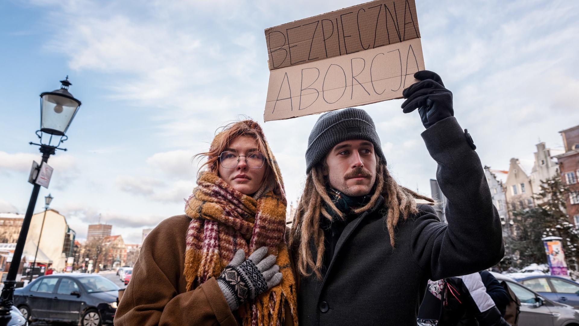 Zwei Demonstrant*innen halten ein Plakat mit der Aufschrift "sichere Abtreibung" in die Luft
