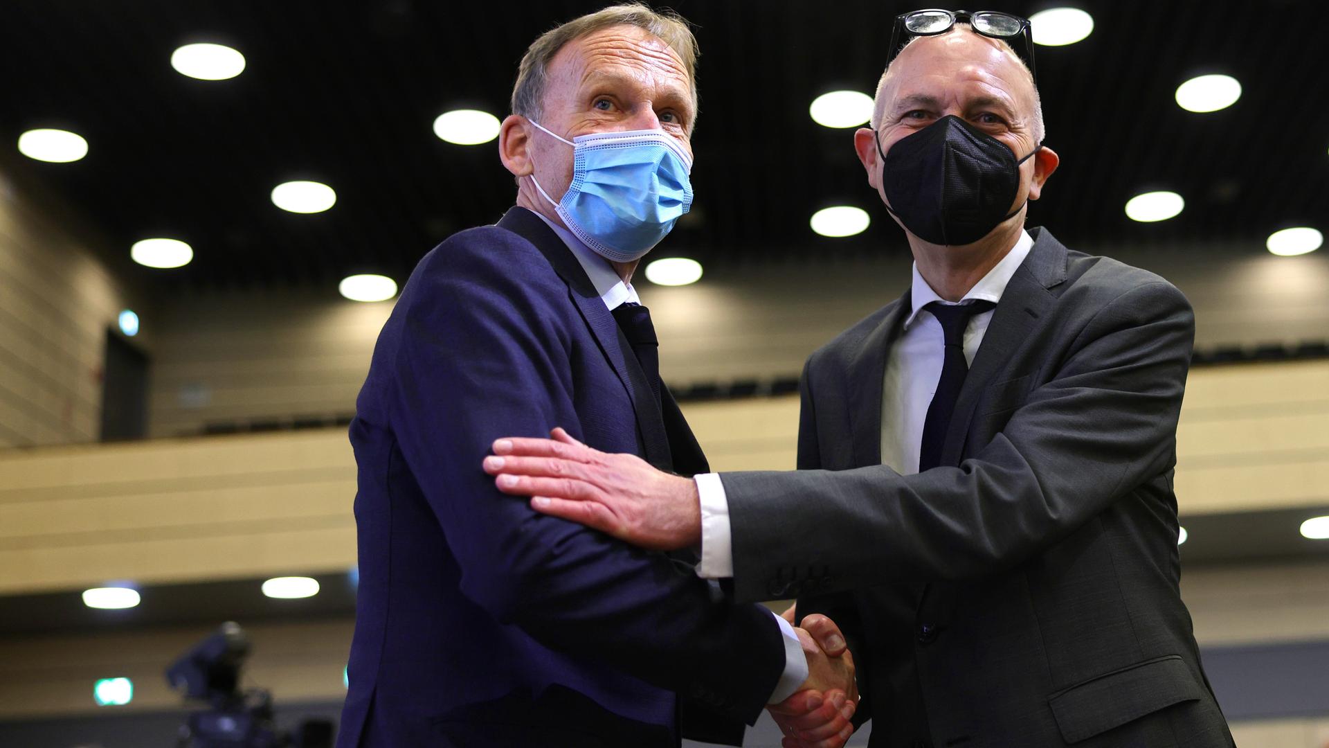 Hans-Joachim Watzke und Bernd Neuendorf schütteln sich die Hand, beide tragen einen Mund-Nasen-Schutz