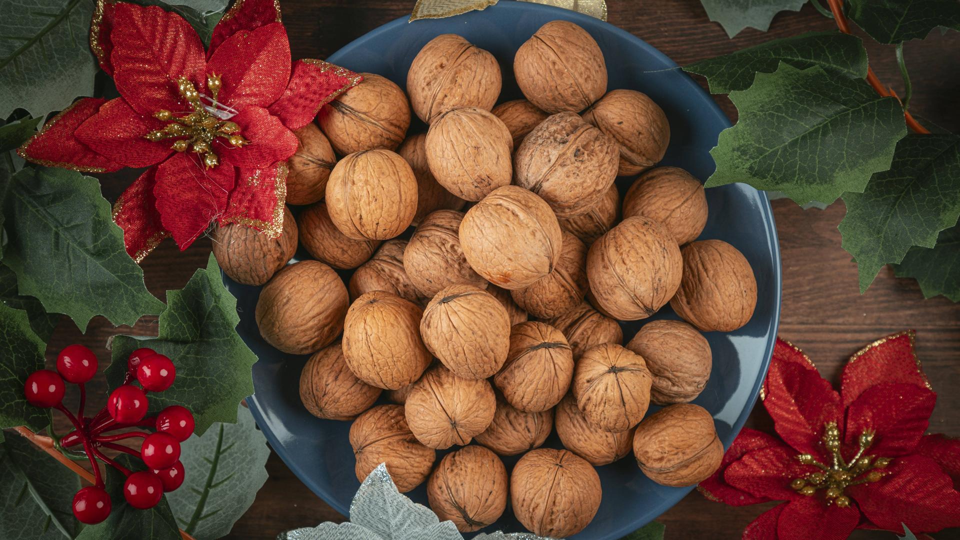 Blauer Teller mit Walnüssen, verziert mit weihnachtlicher Dekoration 