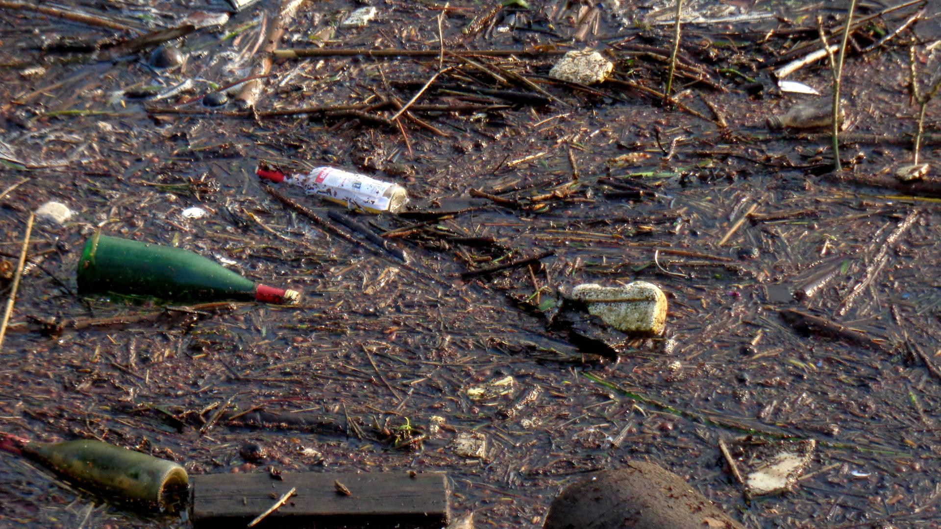 Müll an diversen Stellen im Uferbereich eines Flusses