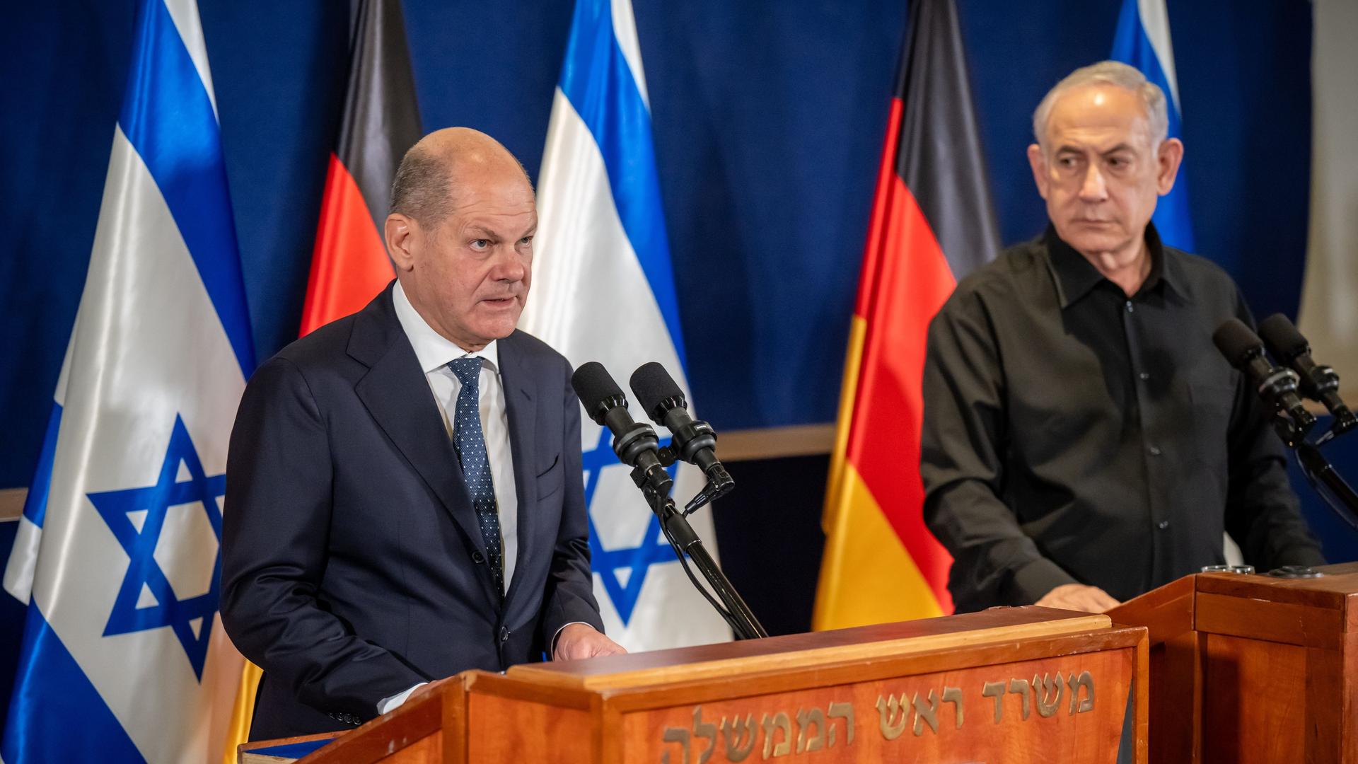 Die beiden stehen an hölzernen Rednerpulten vor den Flaggen ihrer Länder. Scholz sagte gerade etwas; Netanjahu sieht ihn an.