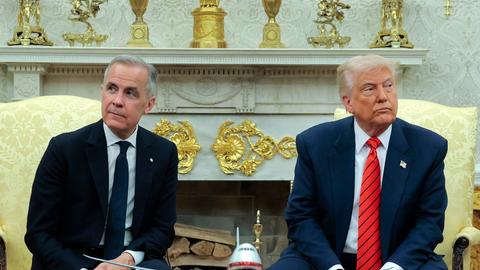 Der kanadische Premierminister Carney sitzt neben US-Präsident Trump. Beide schauen ernst und jeweils in eine andere Richtung. 