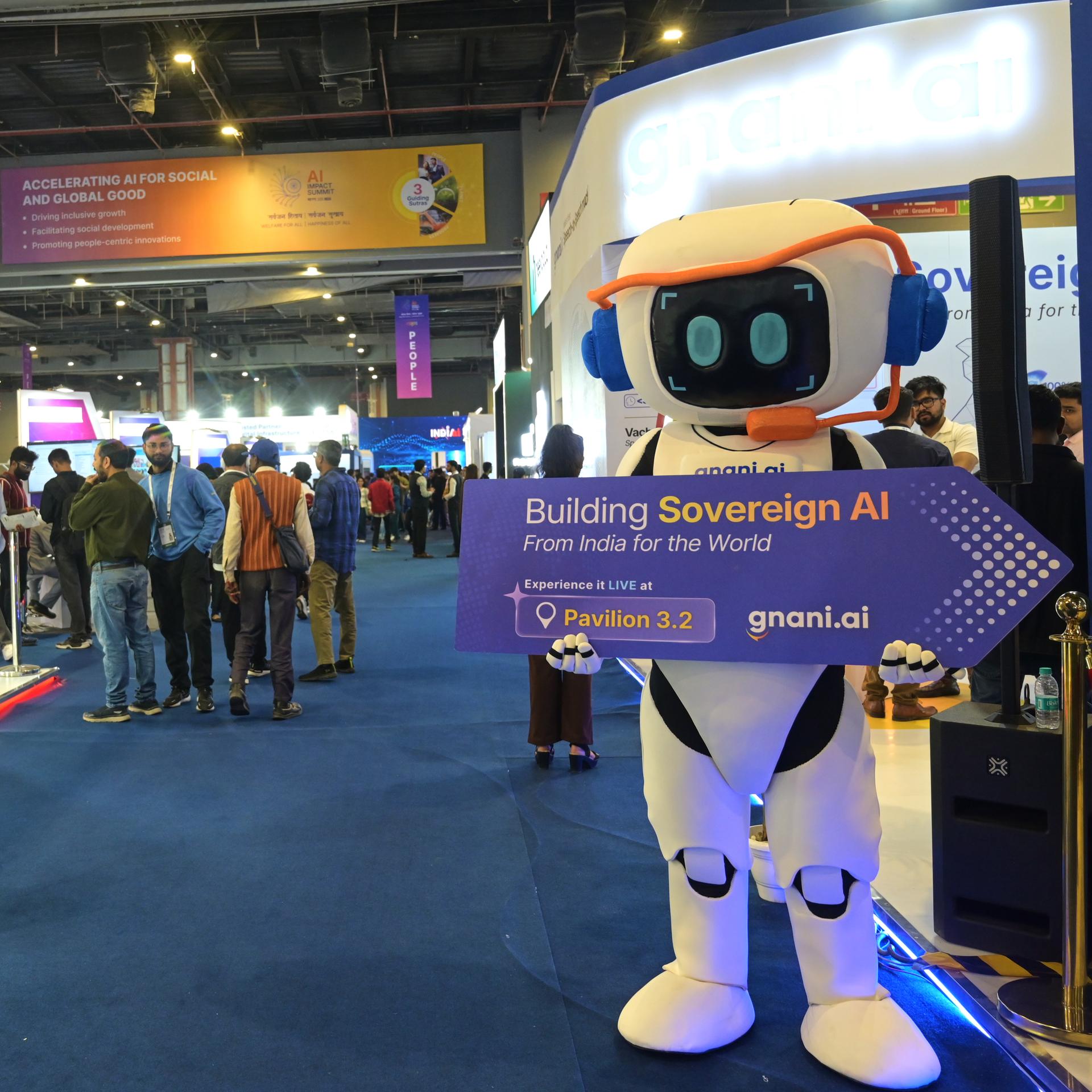Eine Roboterfigur hält ein Schild mit der Aufschrift "Building Sovereign AI" (Entwicklung einer souveränen KI) beim KI-Gipfel im indischen Neu Delhi.