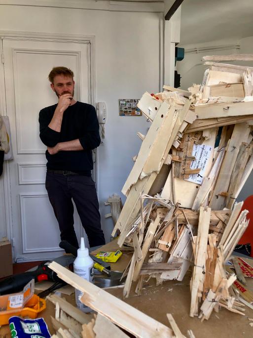 Der Maler Felix Becker in seinem Atelier, er betrachtet eine seiner Skulpturen.