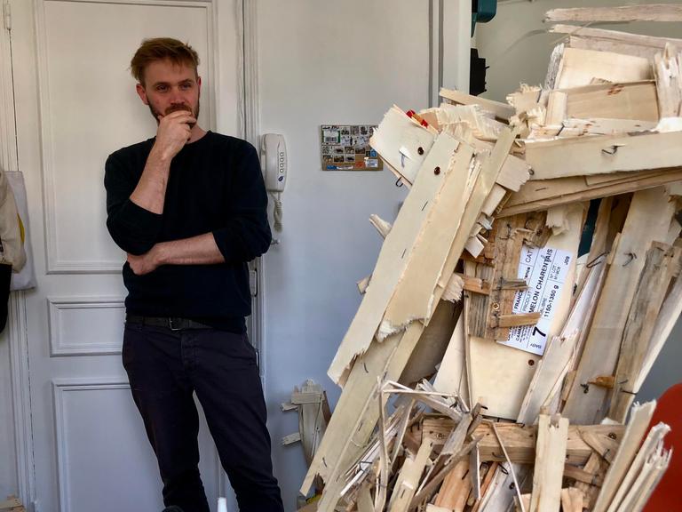 Der Maler Felix Becker in seinem Atelier, er betrachtet eine seiner Skulpturen.
