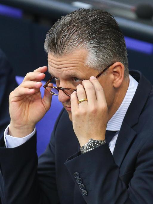 Thorsten Frei, CDU, sitzt im Plenum des Deutschen Bundestags und nimmt seine Brille ab.