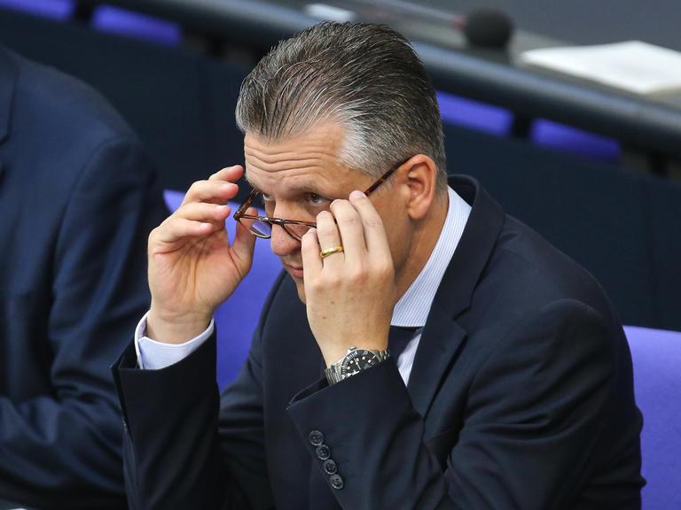 Thorsten Frei, CDU, sitzt im Plenum des Deutschen Bundestags und nimmt seine Brille ab.