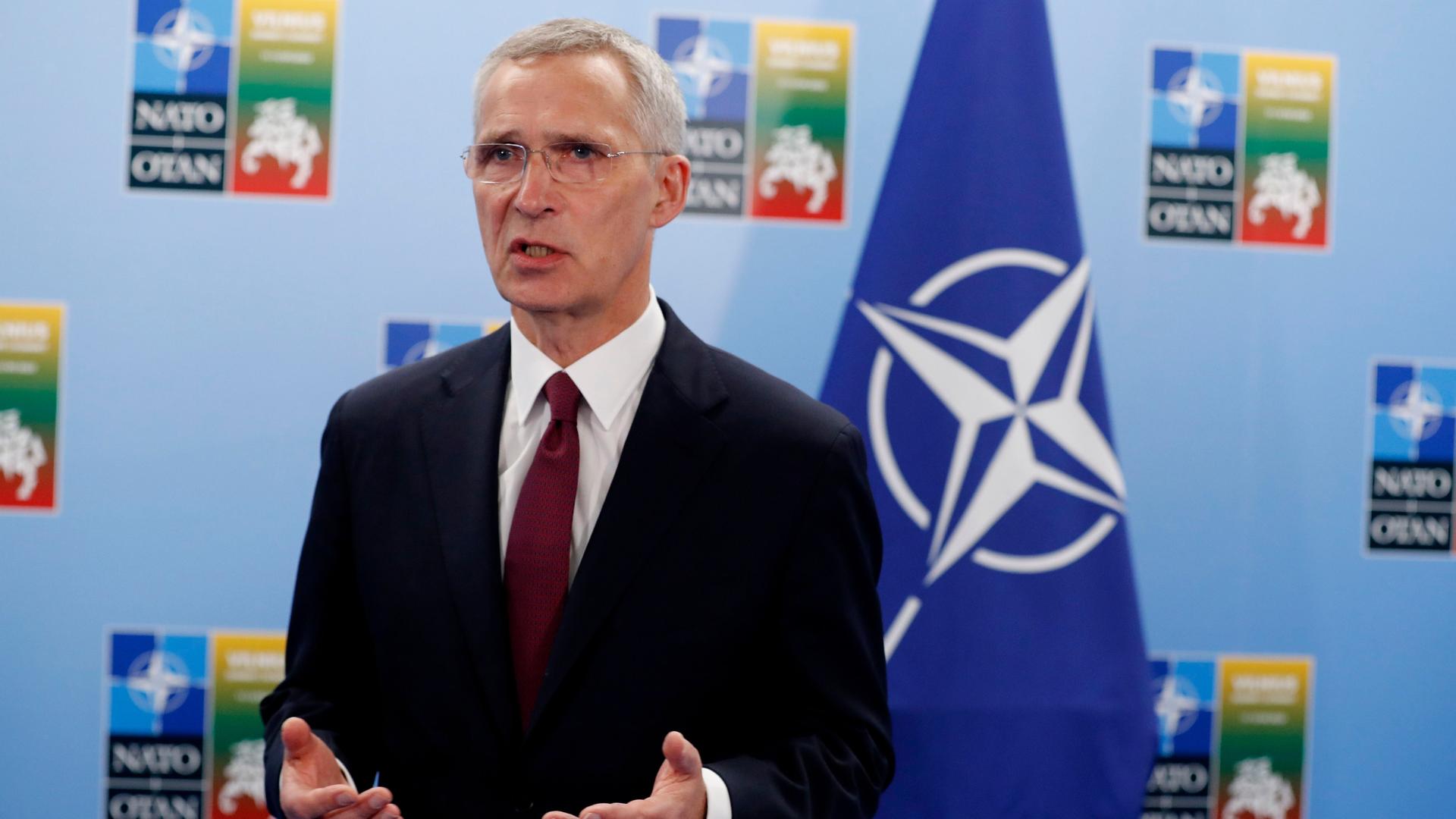 Stoltenberg bei einer Pressekonferenz. Im Hintergrund ist eine blaue Flagge mit dem Symbol der NATO zu sehen.