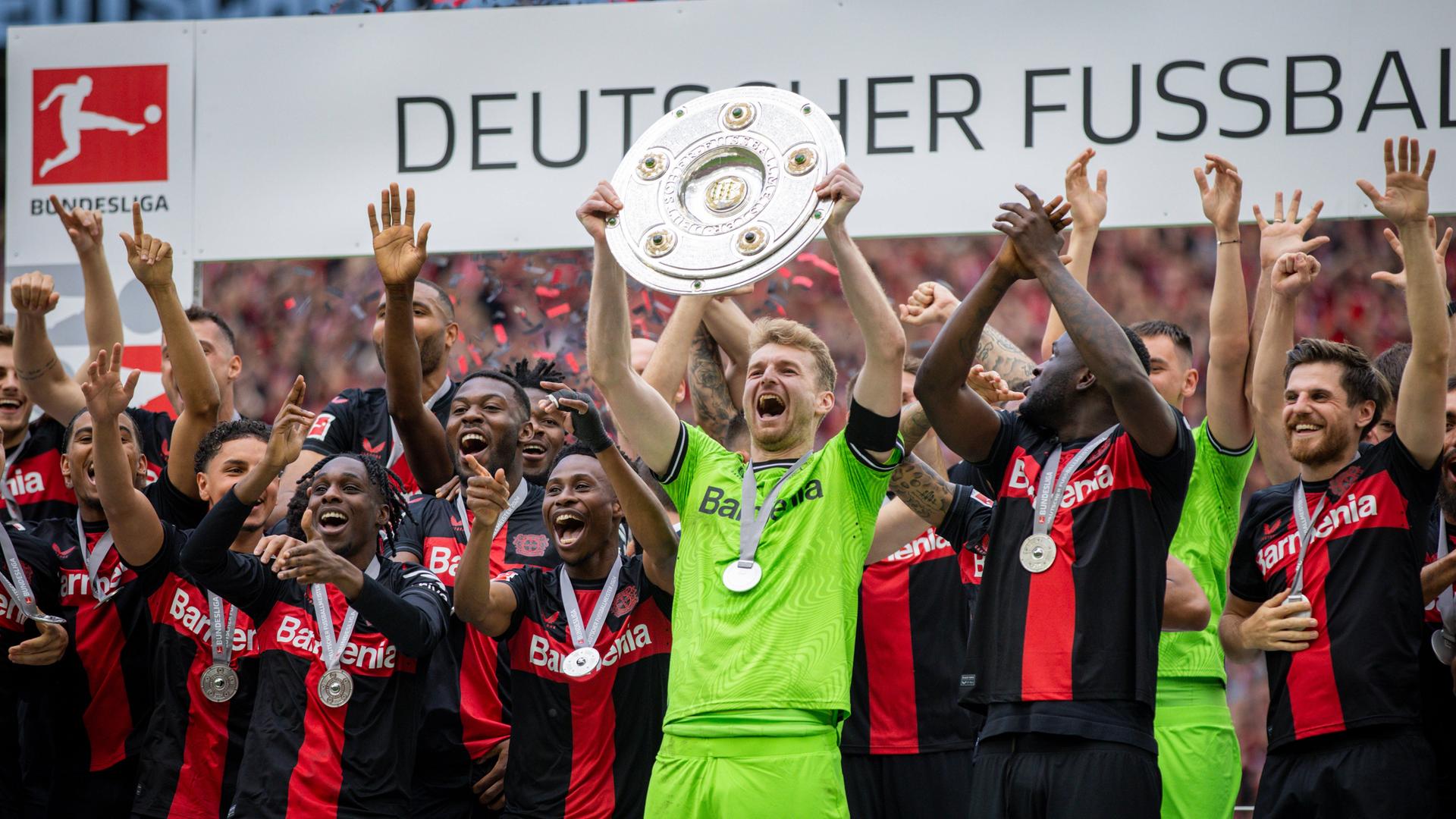 Die Mannschaft von Bayer 04 Leverkusen feiert die Meisterschaft und Torwart Lukas Hradecky hebt die Meisterschale hoch.