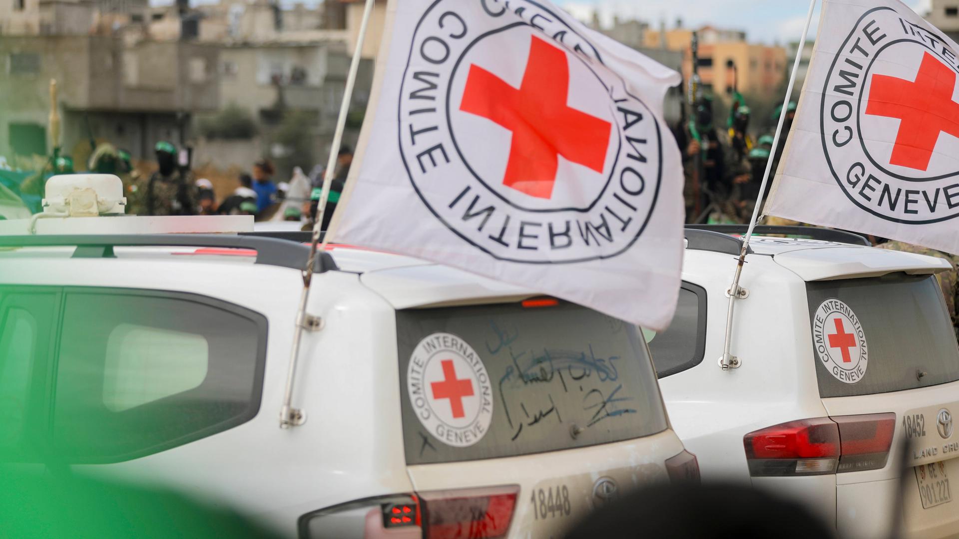 Zwei Wagen vom Roten Kreuz mit Logo-Fahnen stehen in Gaza-Stadt.