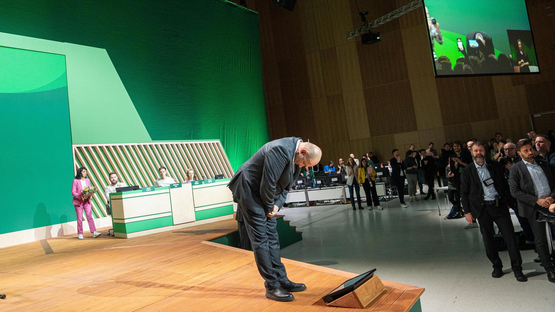 Der scheidende Parteivorsitzende Omid Nouripour verbeugt sich auf einer Bühne vor den Delegierten. 