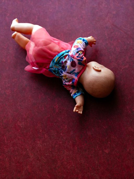Eine Spielzeugpuppe liegt auf einem PVC-Fußboden. (Symbolbild)