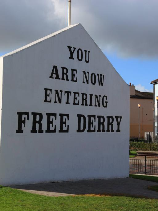 Auf einer weißen Hauswand steht in großer Schrift "You are now entering free derry" 