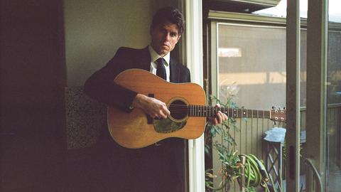 Wir sehen einen Mann mit akustischer Gitarre. 