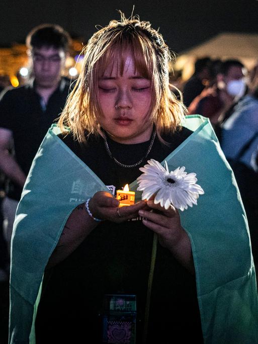 Menschen halten elektrische Kerzen, während sie an einer Mahnwache zum 35. Jahrestag des Tiananmen-Massakers von 1989 teilnehmen.