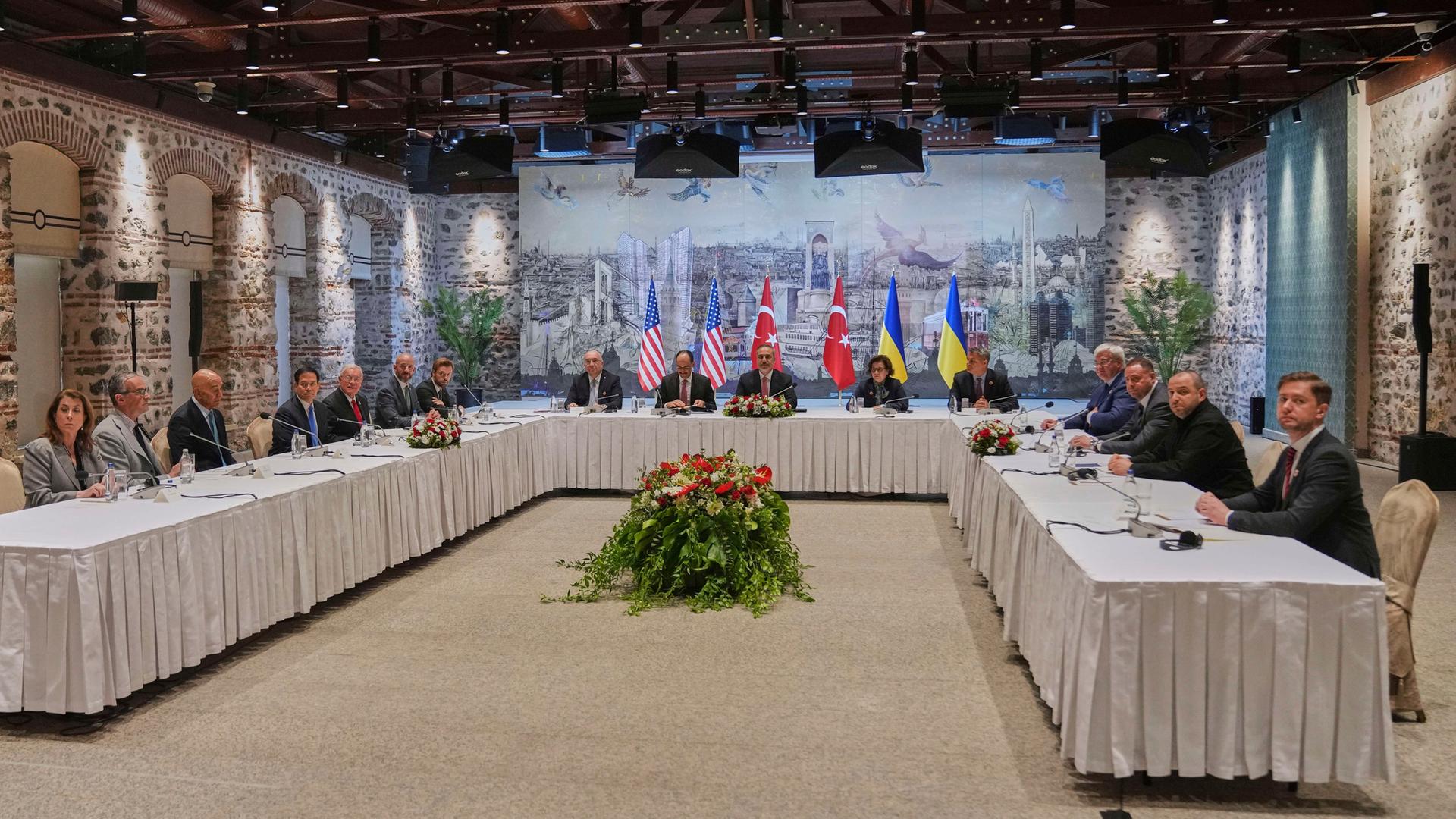 Blick auf lange Tische mit weißen Tischdecken, die zu einem U zusammengestellt sind. Links sitzen Vertreter der USA, vor Kopf Vertreter der Türkei, rechts Vertreter der Ukraine. Blick auf lange Tische mit weißen Tischdecken, die zu einem U zusammengestellt sind. Links sitzen Vertreter der USA, vor Kopf Vertreter der Türkei, rechts Vertreter der Ukraine.