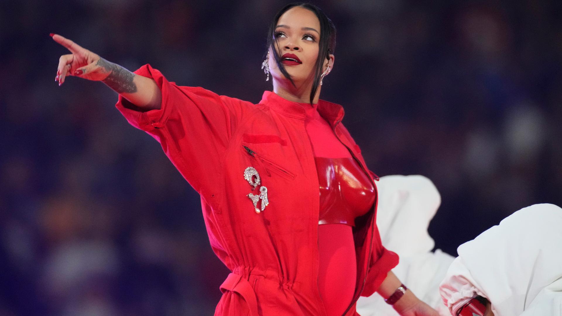 Die Pop-Sängerin Rihanna steht in einem roten Overall auf der Bühne.