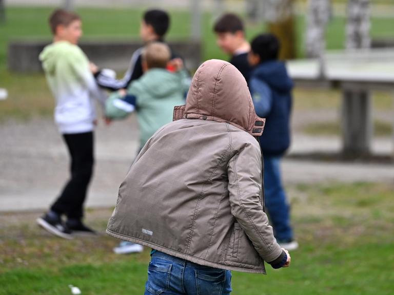 Schüler halten sich auf dem Schulhof einer Grundschule auf und tollen herum.  