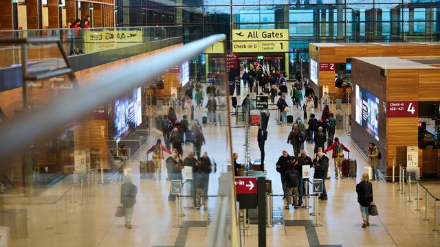 Blick in die Abfertigungshalle des Flughafens Berlin-Brandenburg: Anzeigetafeln, Hinweisschilder, Menschen mit Gepäck.