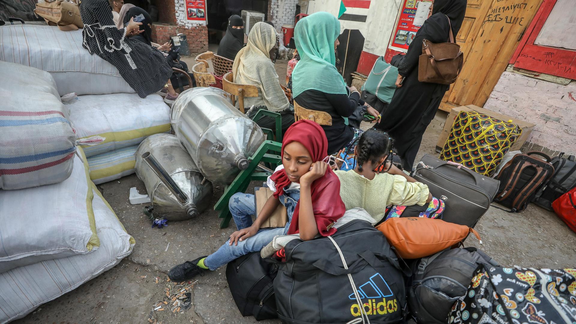 Eine Gruppe von Frauen und Kindern sitzt in der ägyptischen Hauptstadt Kairo mit großen Gepäckstücken auf einer Straße