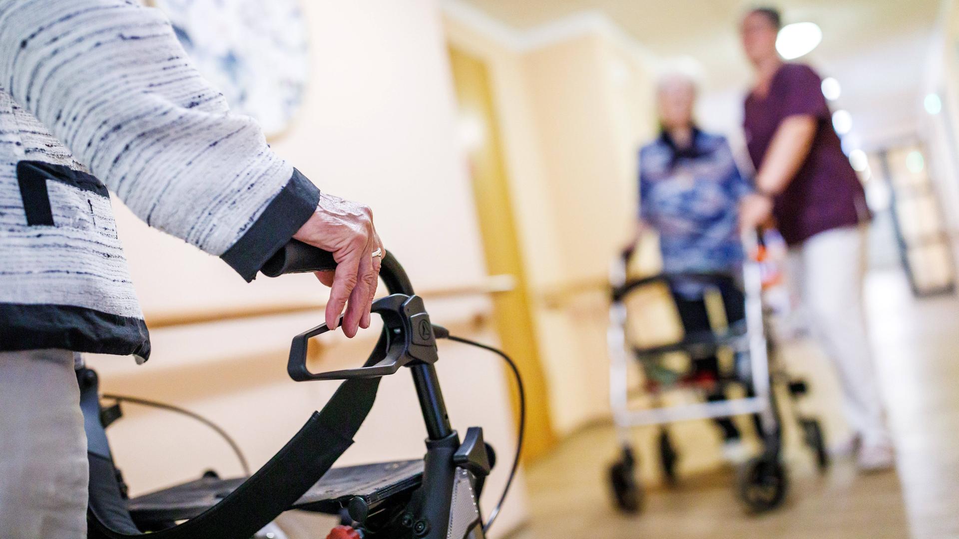 Senioren mit Rollator und eine Pflegekraft sind auf einem Gang in einem Pflegeheim in Brandenburg zu sehen (Symbolfoto)