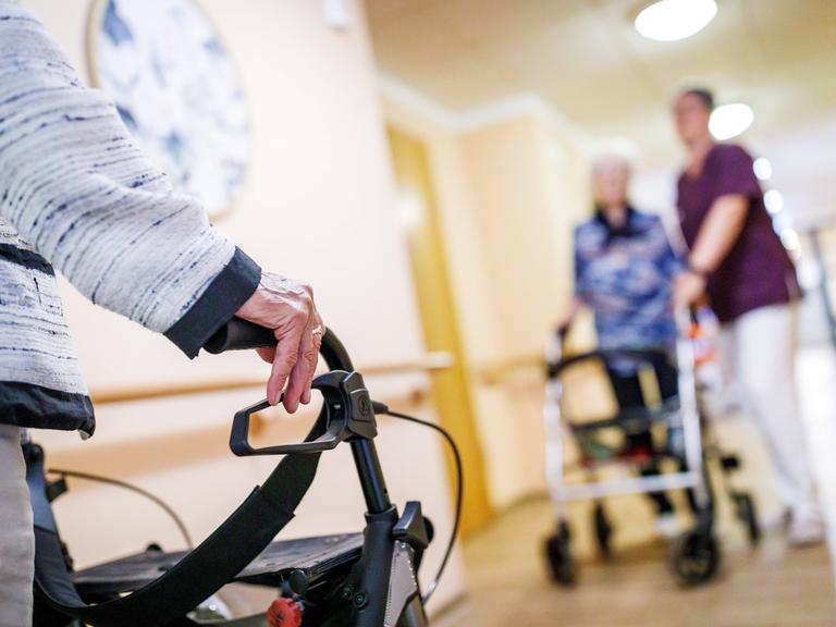 Senioren mit Rollator und eine Pflegekraft sind auf einem Gang in einem Pflegeheim in Brandenburg zu sehen (Symbolfoto)