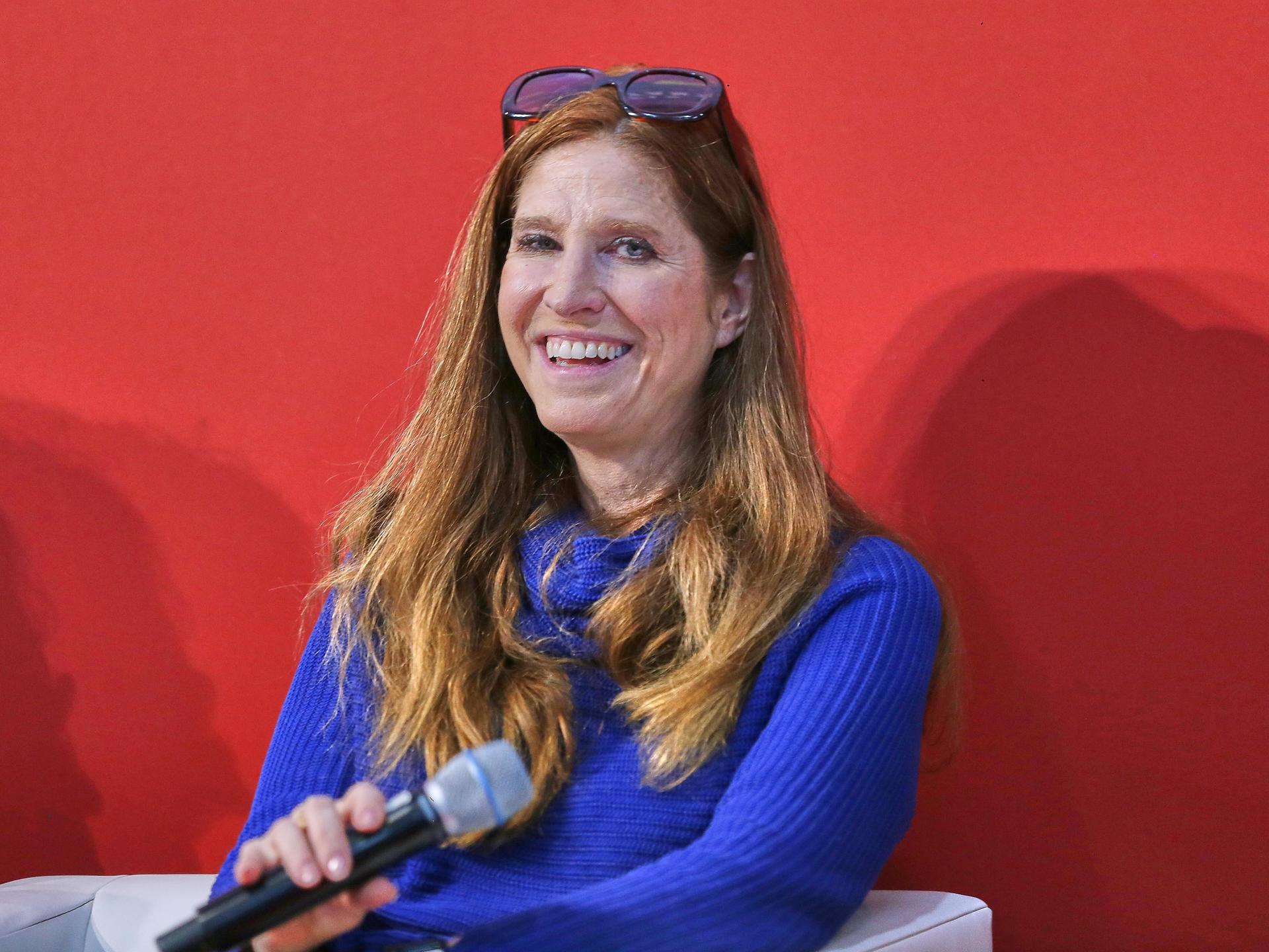Ursula Poznanski bei der Buchmesse: Sie hält ein Mikrofon und lacht ins Publikum. Ursula Poznanski bei der Buchmesse: Sie hält ein Mikrofon und lacht ins Publikum.