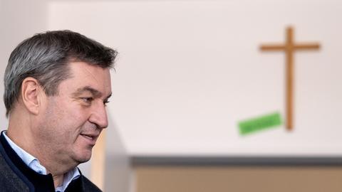 Bayern, München: Markus Söder (CSU), Ministerpräsident von Bayern, steht bei einem Besuch in einer Schulklasse. Im Hintergrund hängt ein Kreuz an der Wand.