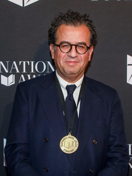 Der Autor Hisham Matar bei der Zeremonie der 75. National Book Awards im Novemeber 2024: Er steht vor einer schwarzen Wand mit dem Logo des Awards (Foto von Andy Kropa/Invision/AP)