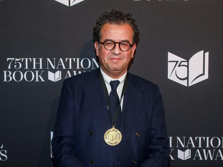 Der Autor Hisham Matar bei der Zeremonie der 75. National Book Awards im Novemeber 2024: Er steht vor einer schwarzen Wand mit dem Logo des Awards (Foto von Andy Kropa/Invision/AP)