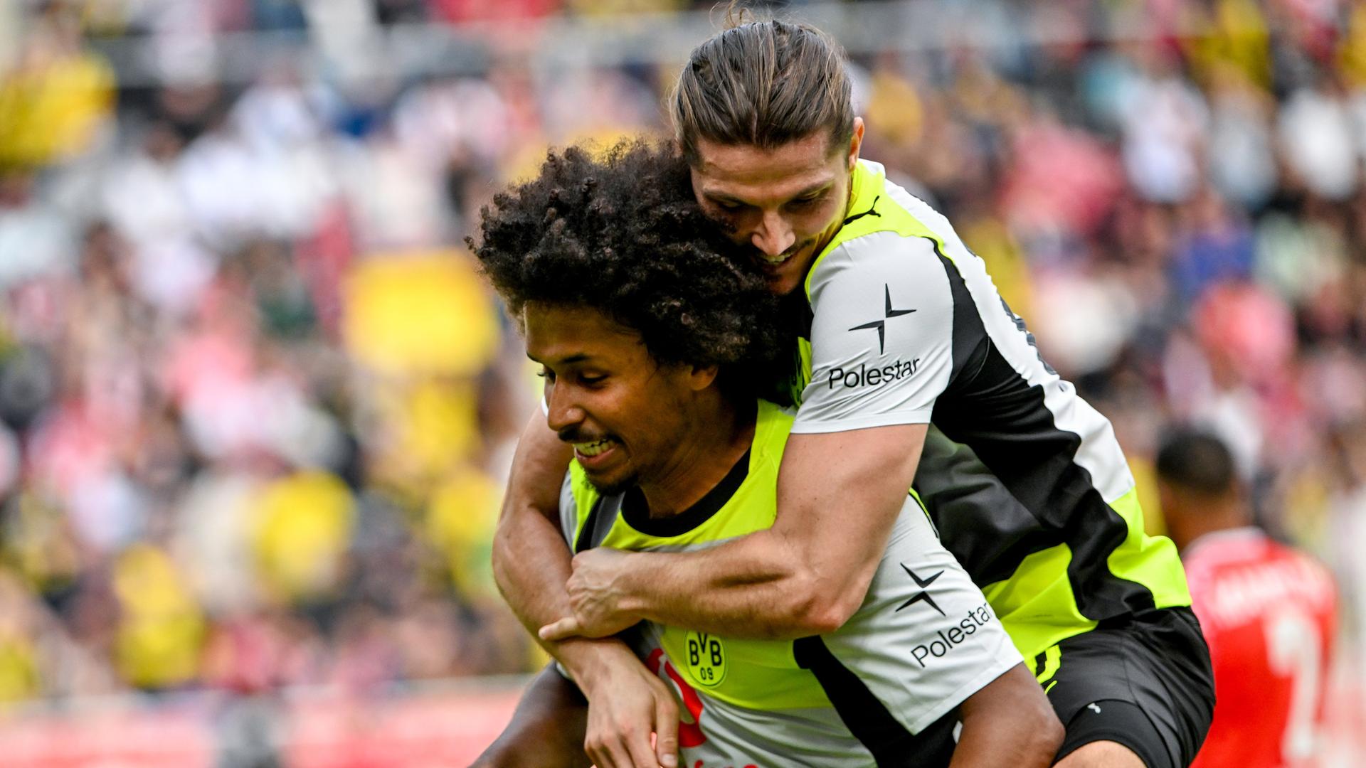 Der Dortmunder Fußballspieler Karim Adeyemi trägt seinen Mannschaftskameraden Marcel Sabitzer Huckepack.